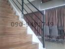 Modern staircase with wooden steps and metal handrail leading to upper level in a residential home