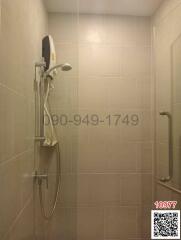 Wall-mounted electric shower unit in a tiled bathroom with safety grab bars