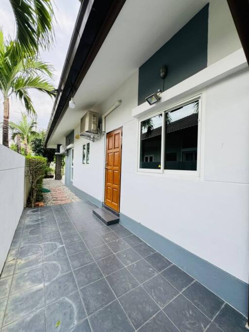 Exterior view of a modern house with grey tiling, white walls, and a wooden door