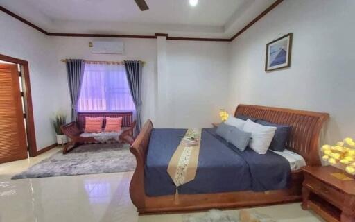 Spacious furnished bedroom with wooden furniture and ample lighting