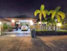 Exterior view of a residential building at night with palm trees