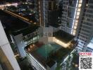 Night view of a luxurious rooftop swimming pool surrounded by high-rise buildings