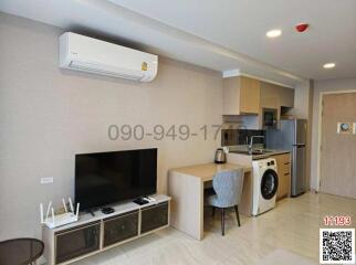 Modern studio apartment with integrated living space featuring kitchen, living area, and appliances