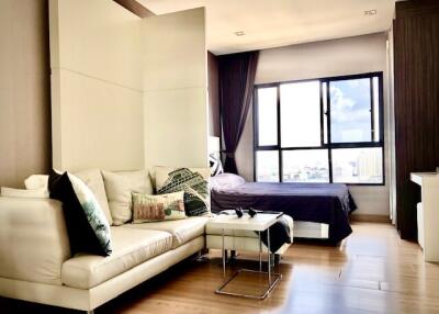 Modern bedroom with large windows and a view, featuring a comfortable bed and a cozy seating area