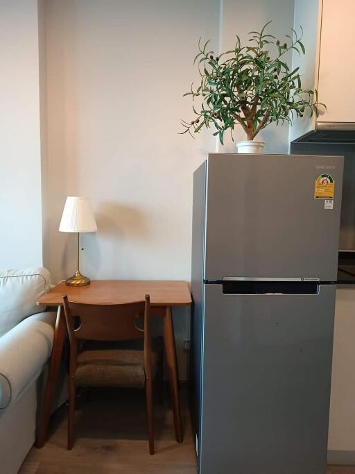 Compact kitchen space with refrigerator, small dining table, and decorative plant