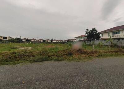 Overcast view of a residential neighborhood showing a vacant lot with houses in the background