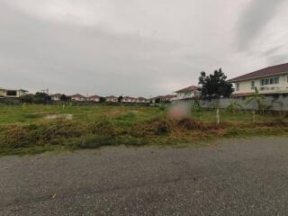 Overcast view of a residential neighborhood showing a vacant lot with houses in the background