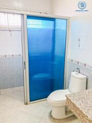 Compact bathroom with toilet, frosted glass shower door, and granite counter