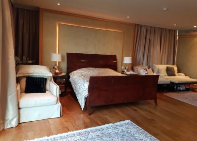 Spacious bedroom with a large bed, elegant furnishings, and ambient lighting