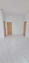 Spacious and well-lit empty room with marble flooring and wooden doors