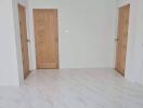 Spacious and well-lit empty room with marble flooring and wooden doors