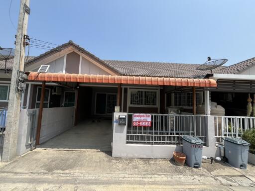 Front view of a suburban residential house with a carport and fence