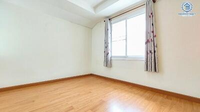 Bright empty bedroom with hardwood floors and a large window