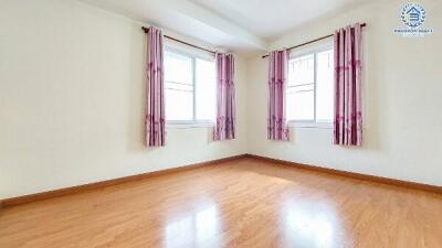 Spacious bedroom with glossy hardwood flooring and large windows with burgundy curtains