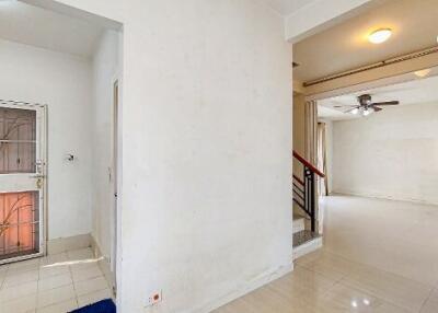 Spacious and bright interior view of a building with tiled floors and wooden staircase