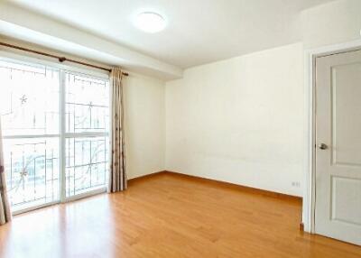 Bright empty bedroom with large window and hardwood floors