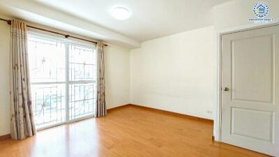 Bright empty bedroom with large window and hardwood floors