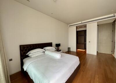 Spacious bedroom with wooden flooring and natural light