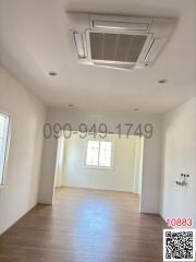 Spacious and well-lit empty living area with large window and air conditioning unit