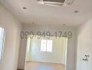 Spacious and well-lit empty living area with large window and air conditioning unit
