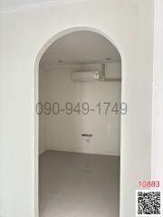 Empty white room with arched doorway and air conditioning unit