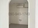 Empty white room with arched doorway and air conditioning unit
