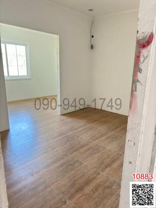 Spacious unfurnished room with wood-like flooring and white walls