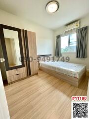 Bright bedroom with a single bed, a wardrobe, and a large window with curtains
