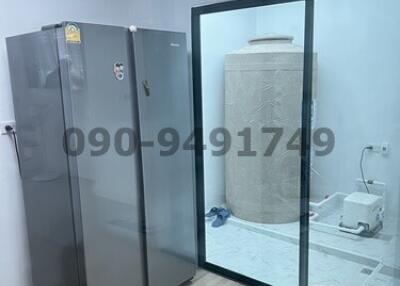 Utility room with a large refrigerator and glass door leading to a bathroom