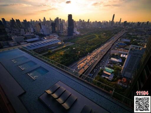 Panoramic city view from a high-rise building with a rooftop pool at sunset