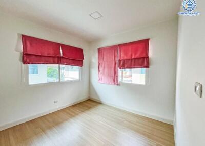 Bright bedroom with red curtains and hardwood floors