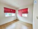 Bright bedroom with red curtains and hardwood floors