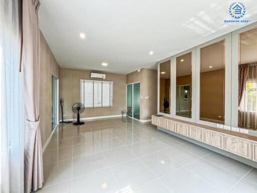 Spacious and well-lit living room with large mirrors and modern tile flooring