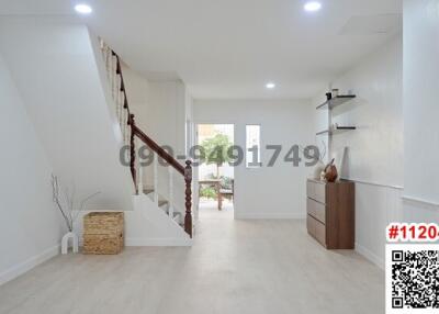 Spacious and bright hallway interior with wooden flooring and staircase
