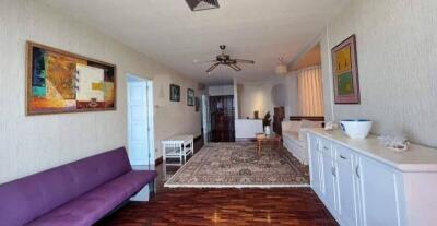 Spacious living room with wooden flooring, natural light, and wall art