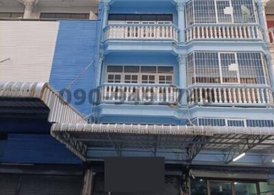 Blue multi-story residential building with balconies and shopfront