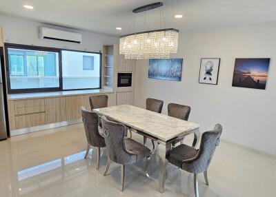 Modern dining room interior with large table, chairs, and kitchen appliances