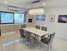 Modern dining room interior with large table, chairs, and kitchen appliances