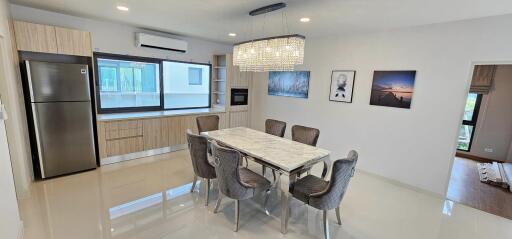 Modern dining room interior with large table, chairs, and kitchen appliances