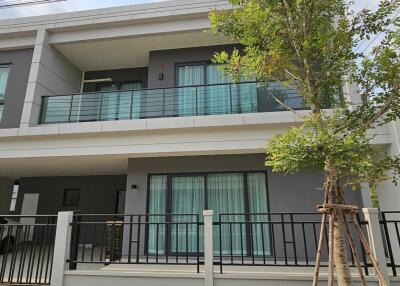 Modern two-story residential home with balcony and tree in front