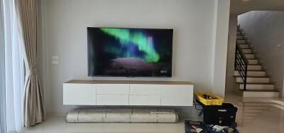 Spacious living room with modern tv and staircase