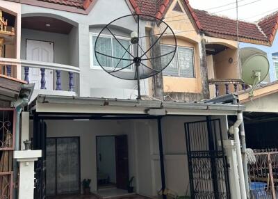 Exterior view of a two-story residential townhouse with satellite dishes