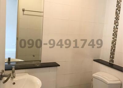 Compact bathroom with white fixtures, mirror and tiled wall