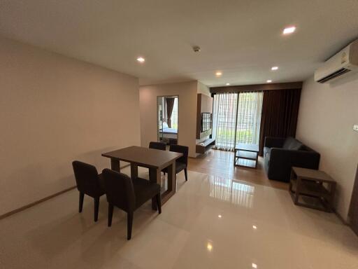 Spacious and well-lit living room with glossy tiled flooring, large windows and modern furnishings