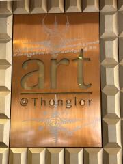 Artistic signboard with intricate design on a textured wall at Thonglor