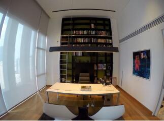 Modern home office with a large bookshelf, oval table, and artwork