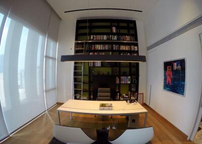 Modern home office with a large bookshelf, oval table, and artwork