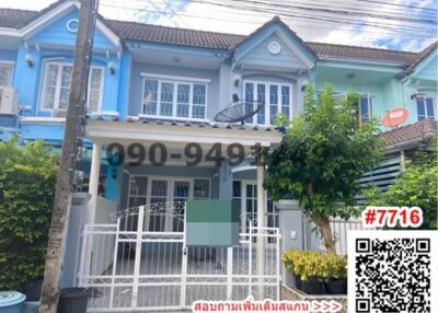 Blue two-story townhouse with white fence under a clear sky