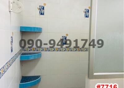 Compact tiled bathroom with blue shelves and white walls