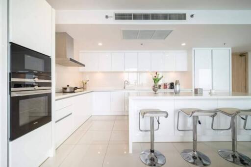 Modern white kitchen with stainless steel appliances and bar stools